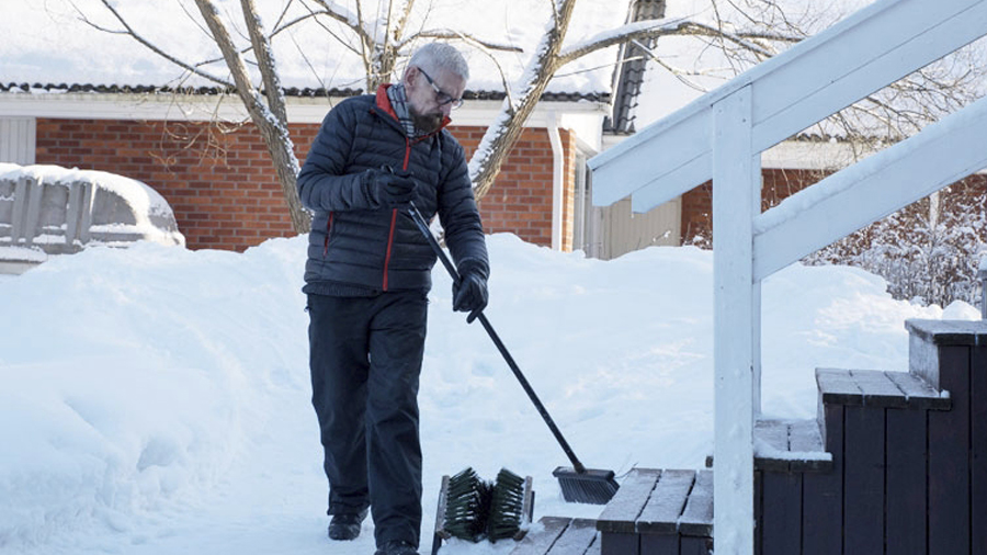 En man borstar snö.